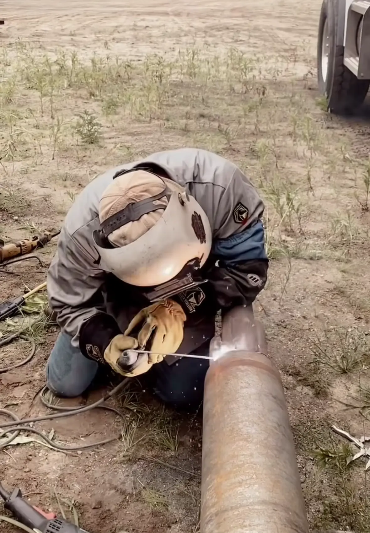 Zac stick welding a large steel pipe joint outdoors on a job site